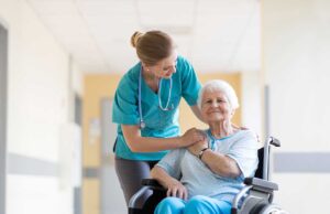 Caregiver helps an older resident sanitize hands in a clean assisted living common area.