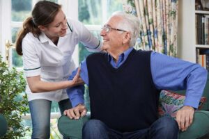 Two older adults laughing together while playing cards in a sunny common room.